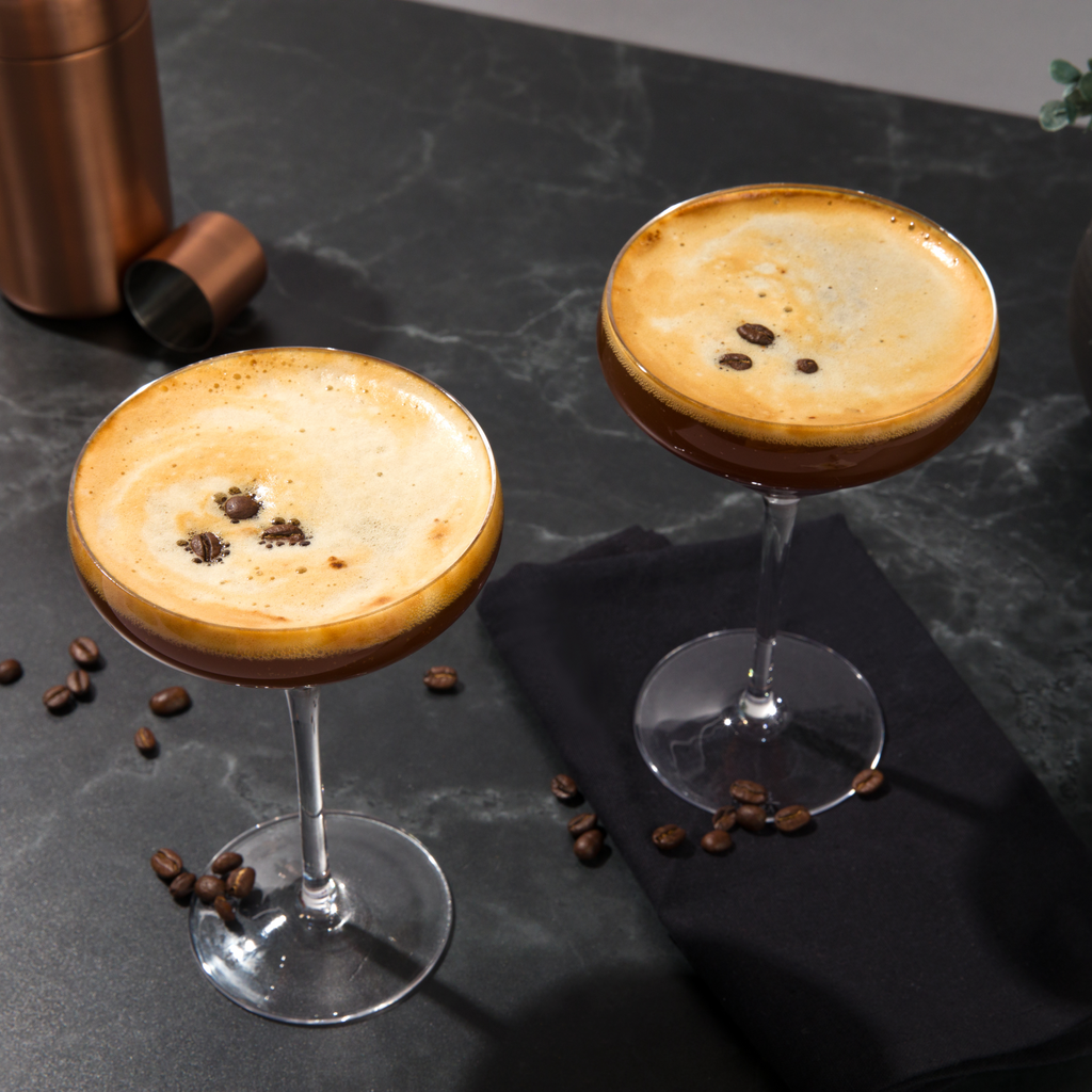Two coffee-themed cocktails with coffee beans on a dark surface